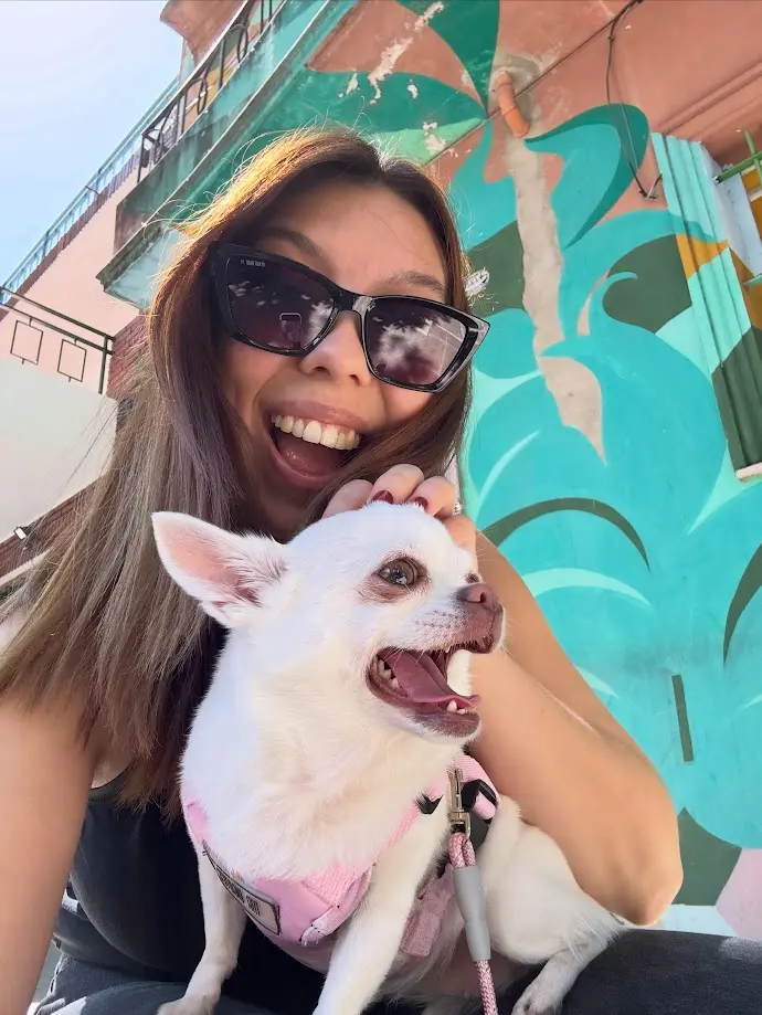 Eva junto a su humana Sofi, sonriendo frente a un mural colorido